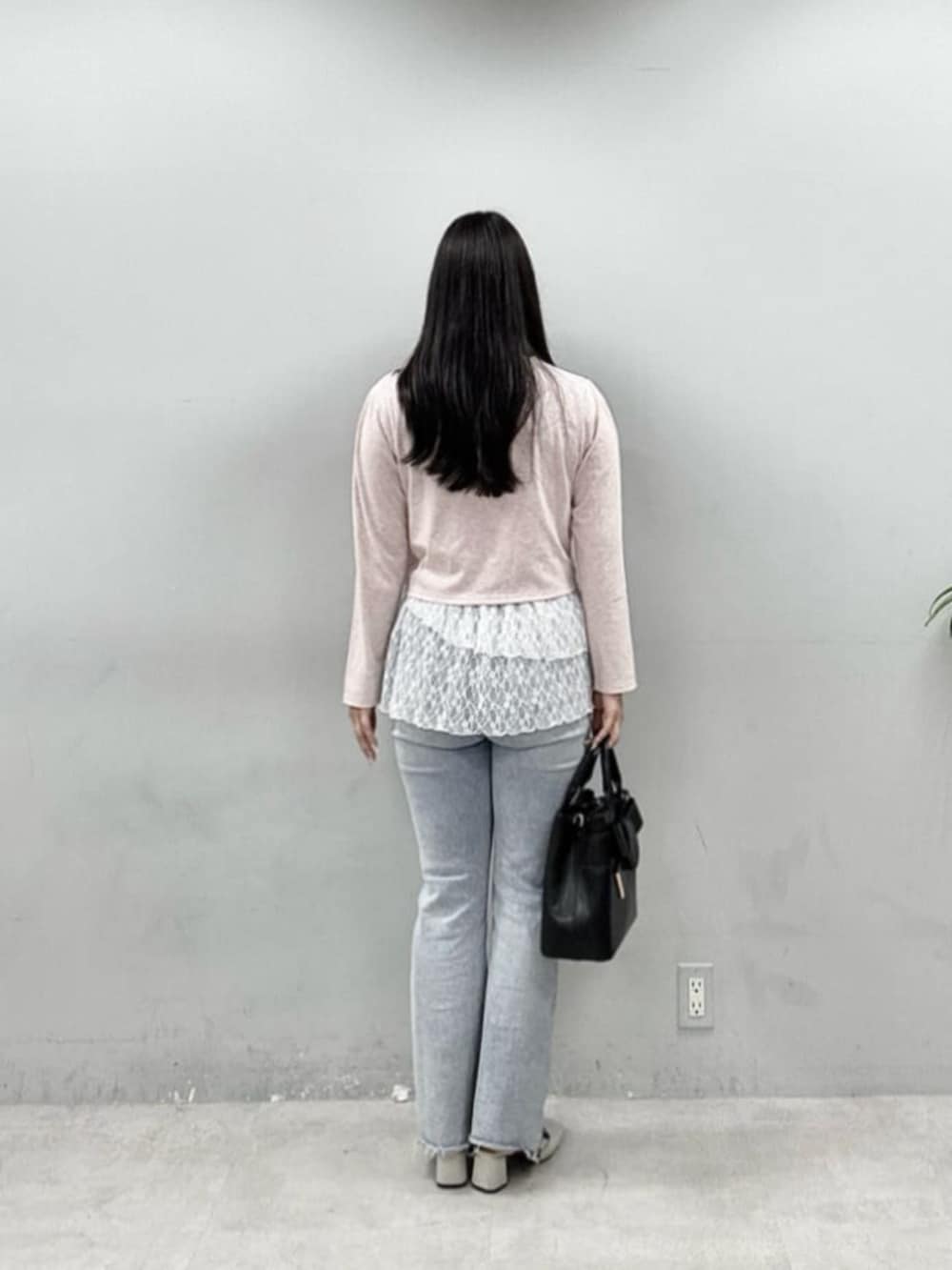 ブルー系のデニムパンツ、ピンク系のカーディガン/ボレロ、ブラック系のショルダーバッグを着用したレディースの春コーディネートの3枚目の写真