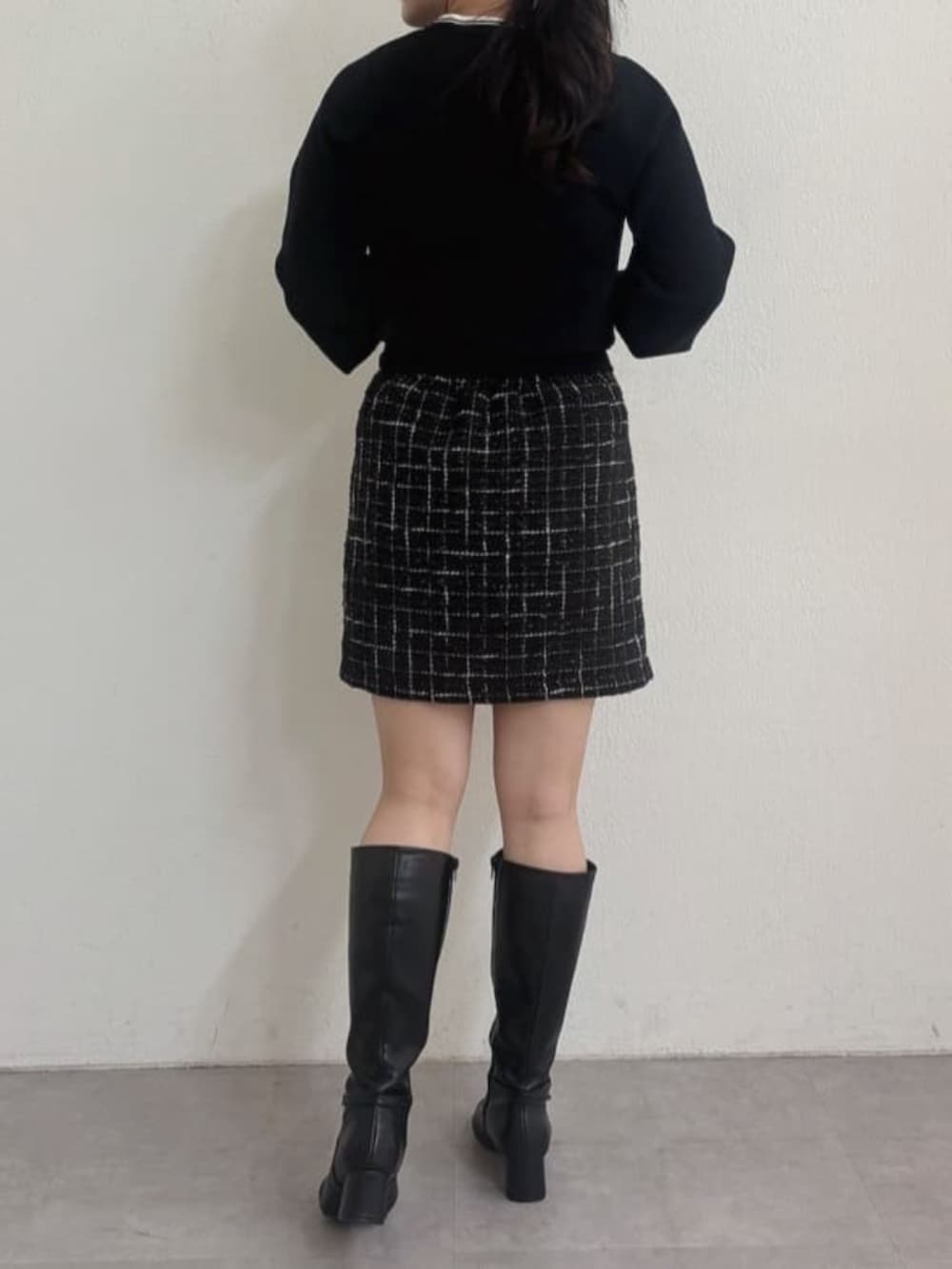 ブラック系のブーツ、ブラック系のスカート、ホワイト系のハンドバッグを着用したレディースの秋コーディネートの3枚目の写真