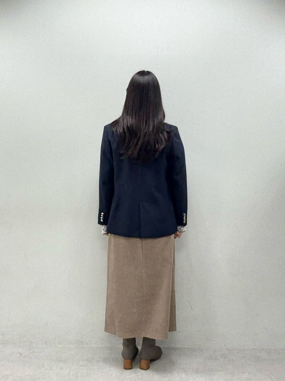 ブラウン系のスカート、ブルー系のテーラードジャケット、グレー系のTシャツ/カットソーを着用したレディースの秋コーディネートの3枚目の写真