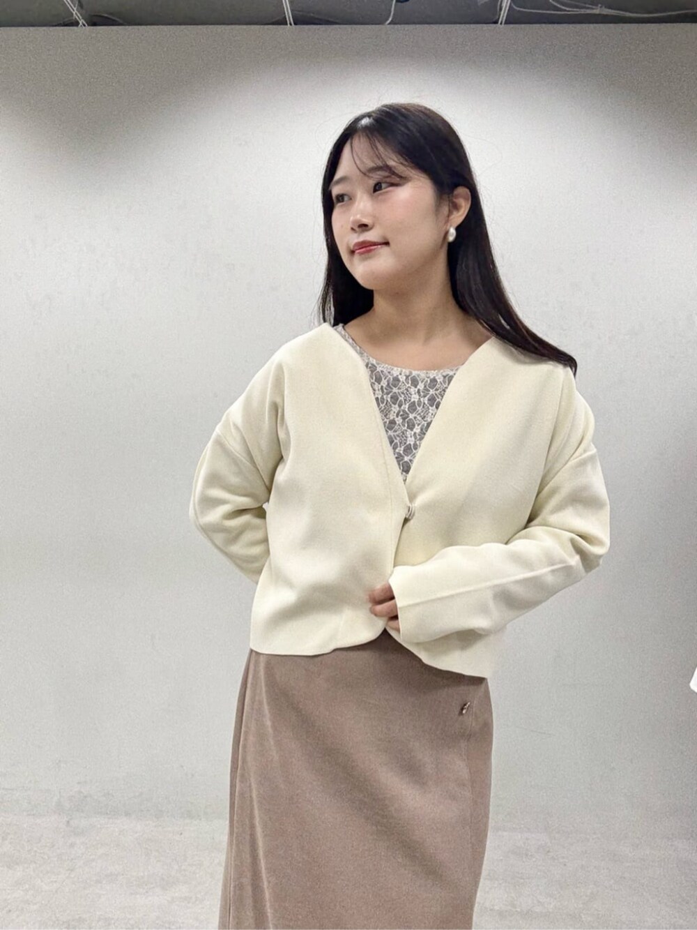 ブラウン系のスカート、グレー系のTシャツ/カットソー、ホワイト系のカーディガン/ボレロを着用したレディースの秋コーディネートの6枚目の写真