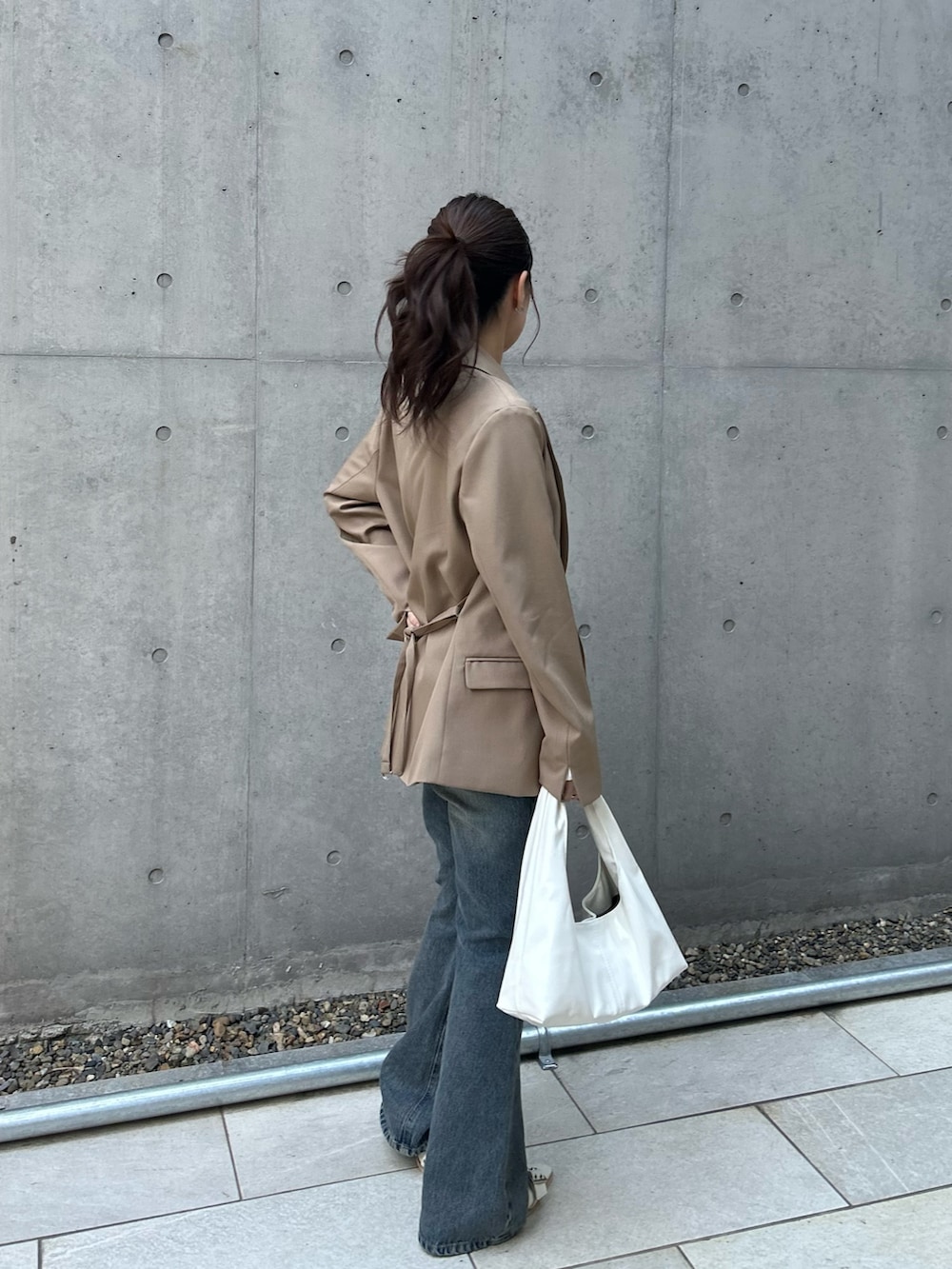 ベージュ系のテーラードジャケット、ホワイト系のカーディガン/ボレロ、ブルー系のデニムパンツを着用したレディースの春コーディネートの2枚目の写真