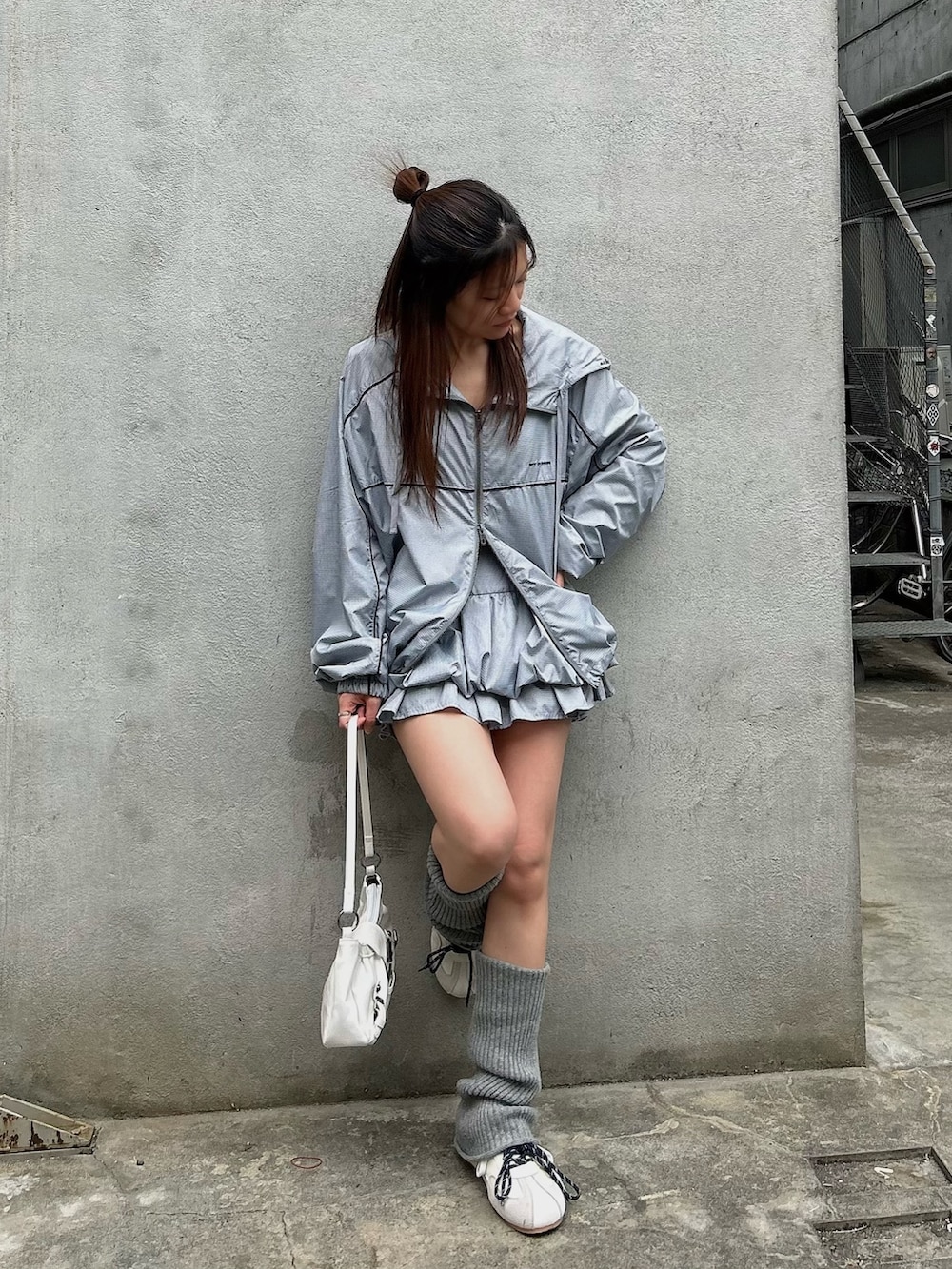 グレー系のブルゾン、グレー系のスカート、ホワイト系のスニーカーを着用したレディースの春コーディネートの4枚目の写真
