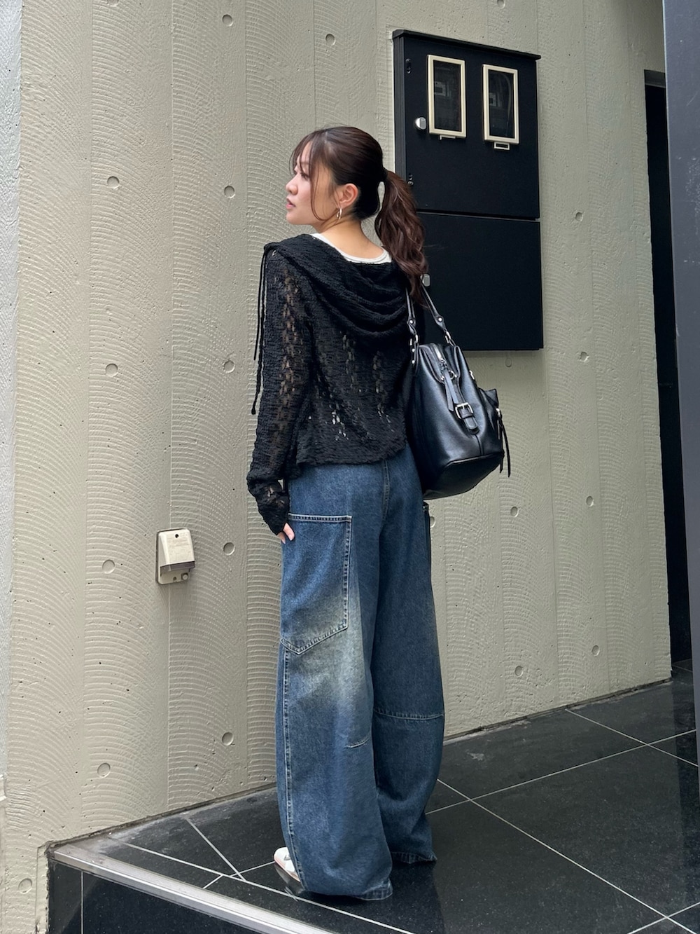 ホワイト系のキャミソール、ブラック系のパーカー、ブルー系のデニムパンツを着用したレディースの春コーディネートの2枚目の写真