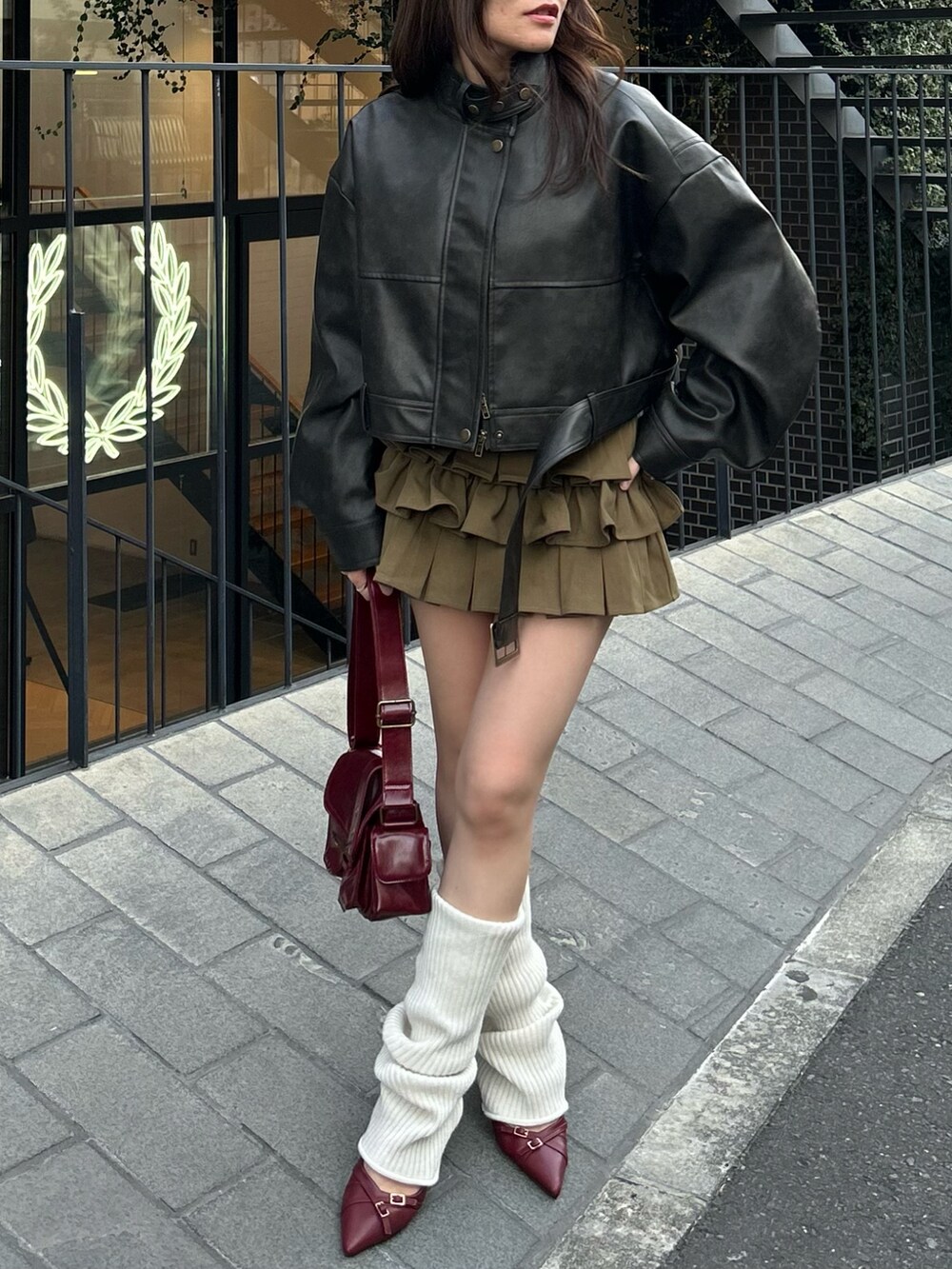 ブラウン系のその他アウター、グリーン系のスカート、ホワイト系のレッグウォーマーを着用したレディースの冬コーディネートの2枚目の写真