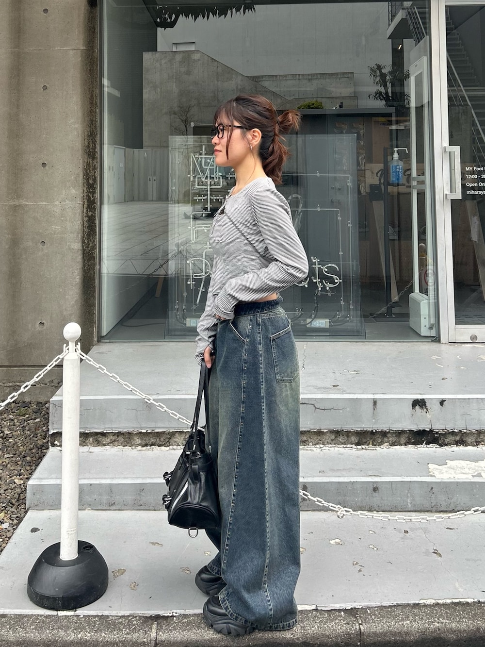 グレー系のTシャツ/カットソー、ブルー系のデニムパンツ、ブラック系のショルダーバッグを着用したレディースの春コーディネートの3枚目の写真