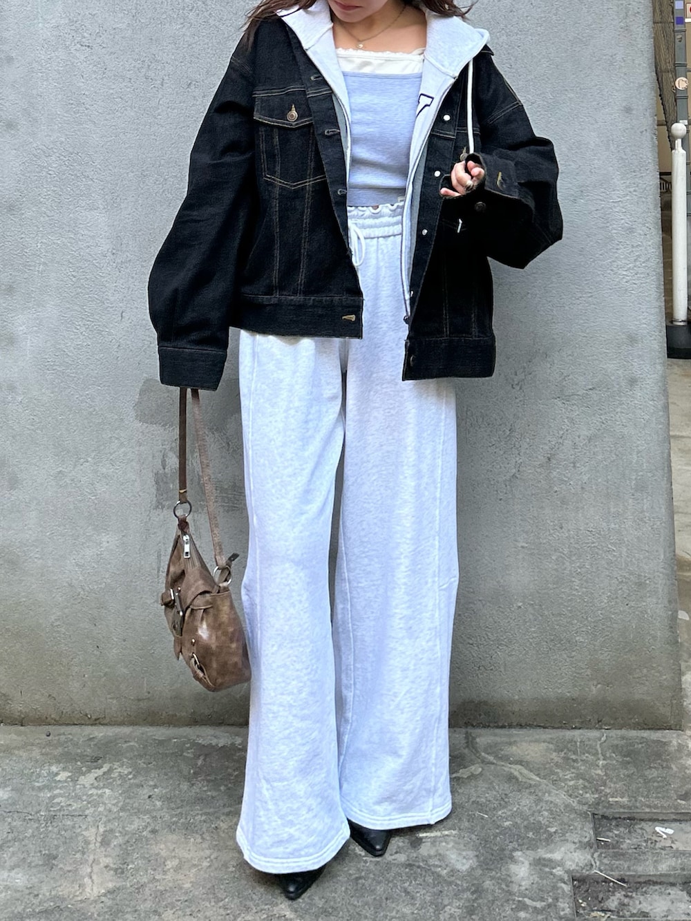 ホワイト系のパーカー、ブラック系のデニムジャケット、グレー系のキャミソールを着用したレディースの春コーディネートの3枚目の写真