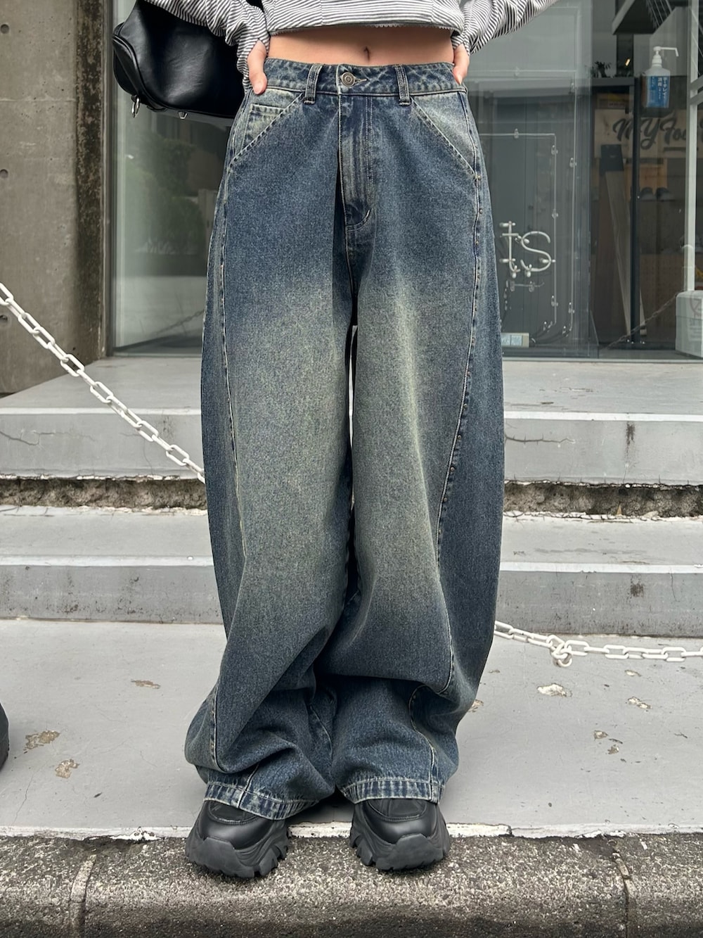 グレー系のTシャツ/カットソー、ブルー系のデニムパンツ、ブラック系のショルダーバッグを着用したレディースの春コーディネートの6枚目の写真