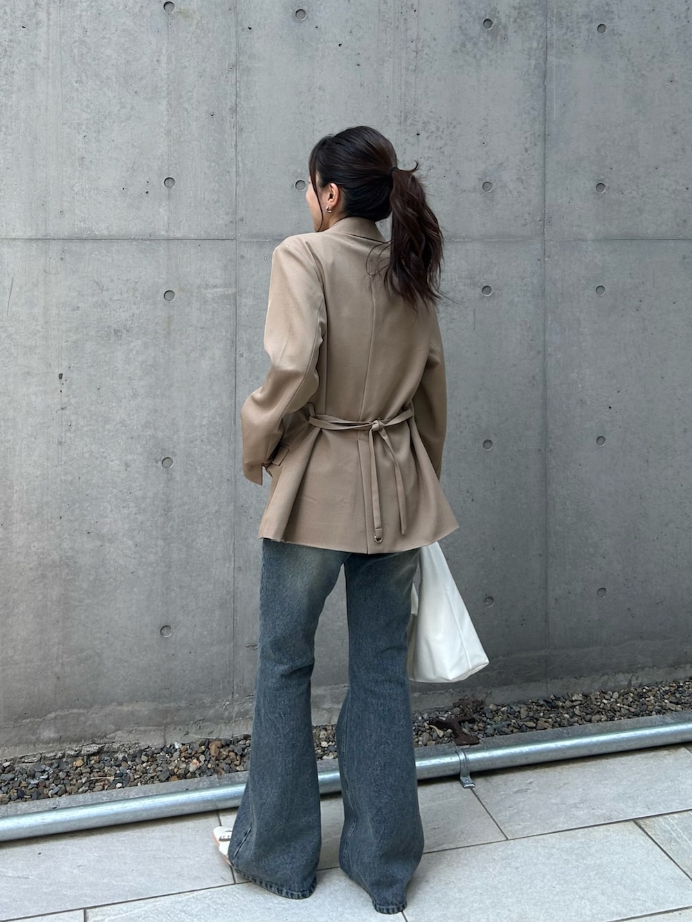ベージュ系のテーラードジャケット、ホワイト系のカーディガン/ボレロ、ブルー系のデニムパンツを着用したレディースの春コーディネートの3枚目の写真