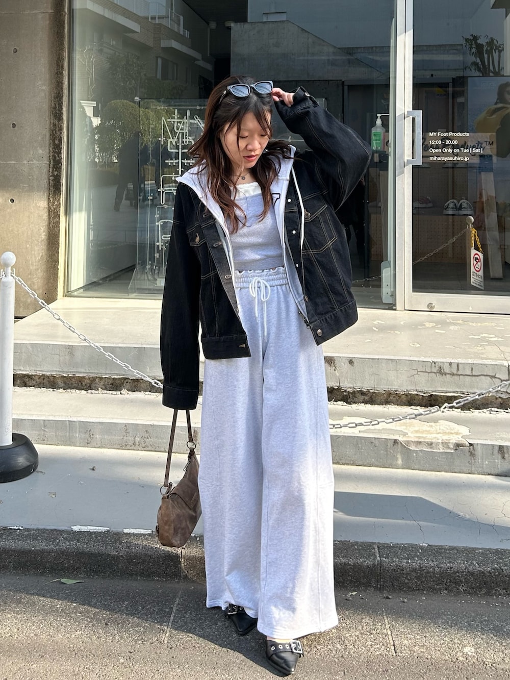 ホワイト系のパーカー、ブラック系のデニムジャケット、グレー系のキャミソールを着用したレディースの春コーディネートの4枚目の写真