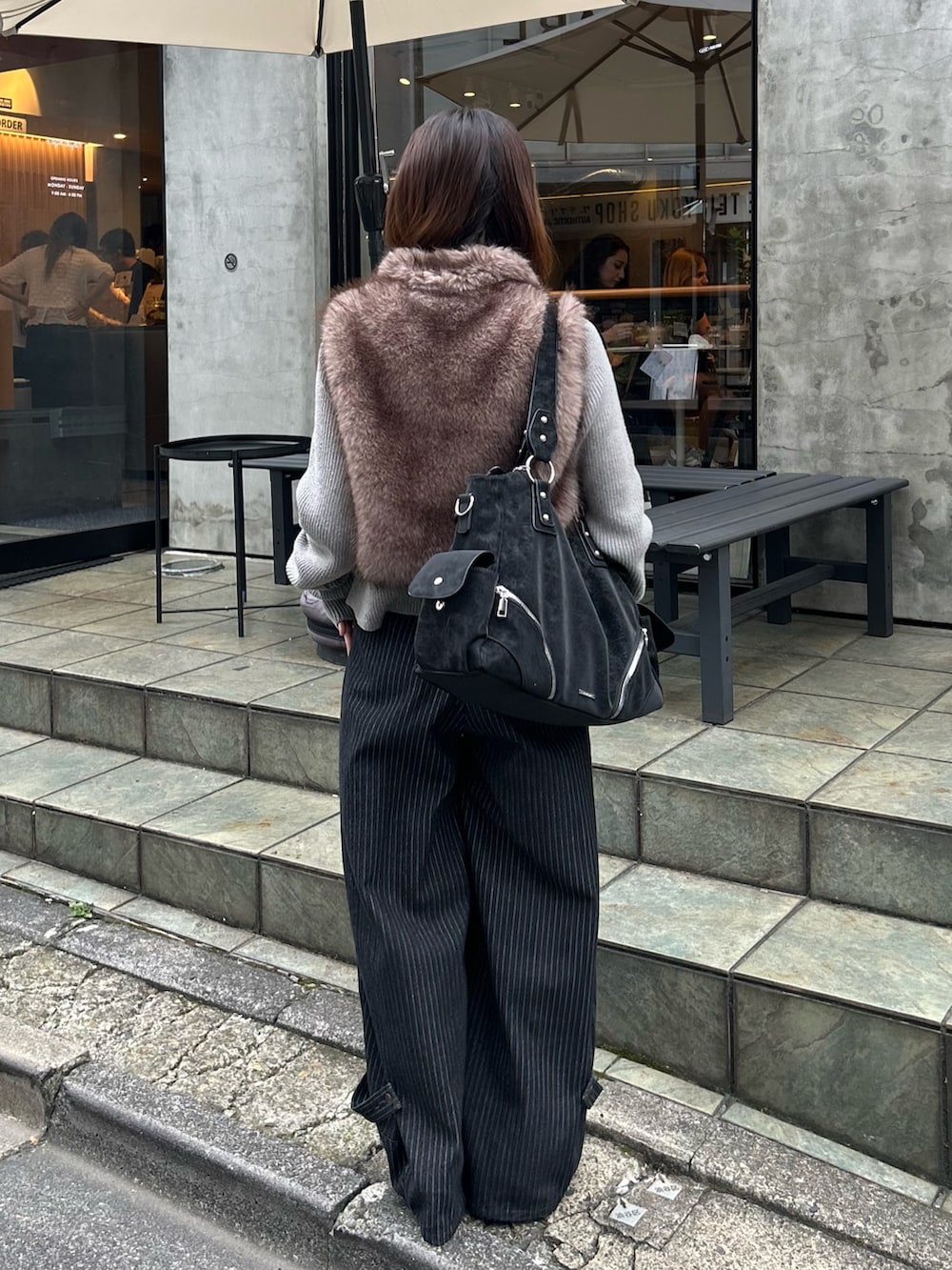 ブラウン系のニット/セーター、ブルー系のデニムパンツ、ブラック系のショルダーバッグを着用したレディースの秋コーディネートの2枚目の写真
