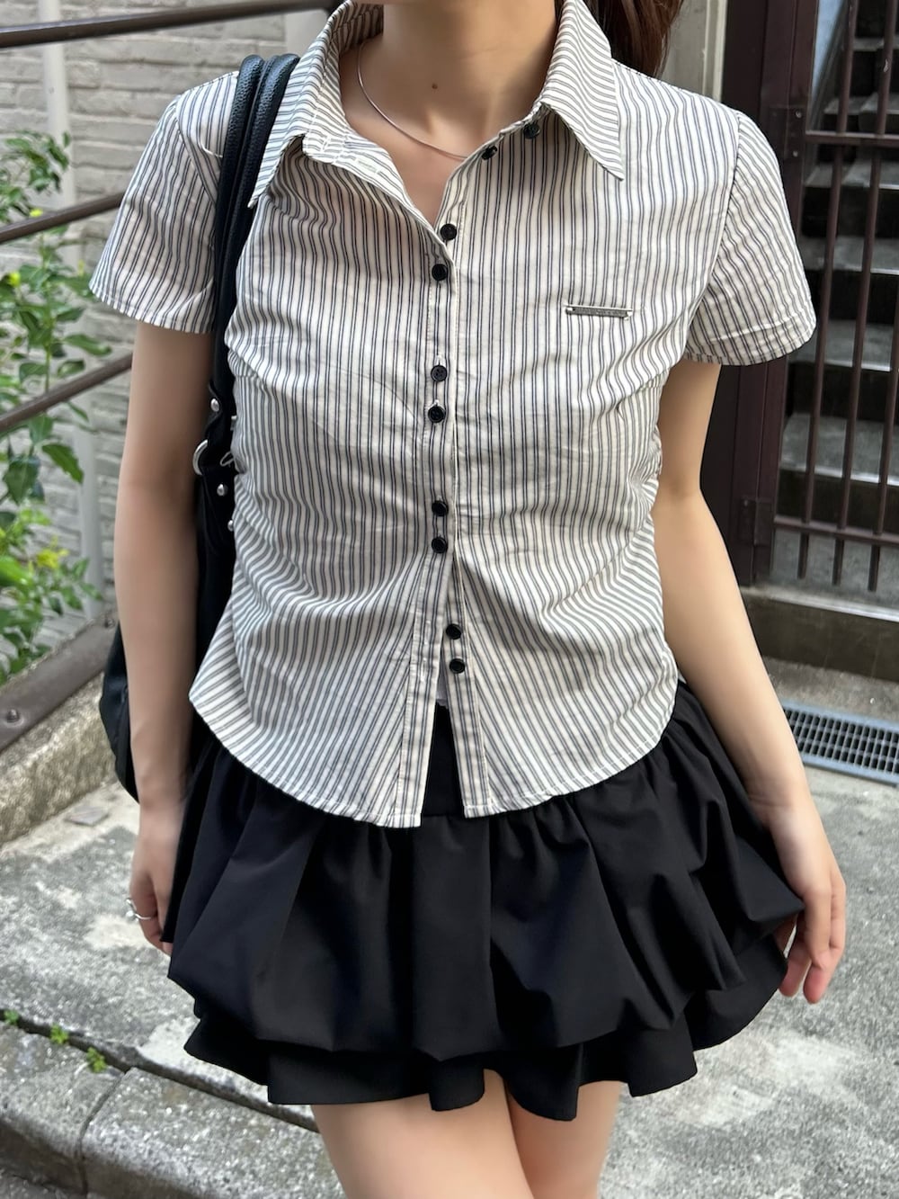 ホワイト系のシャツ/ブラウス、ブラック系のスカート、ブラック系のブーツを着用したレディースの春コーディネートの4枚目の写真