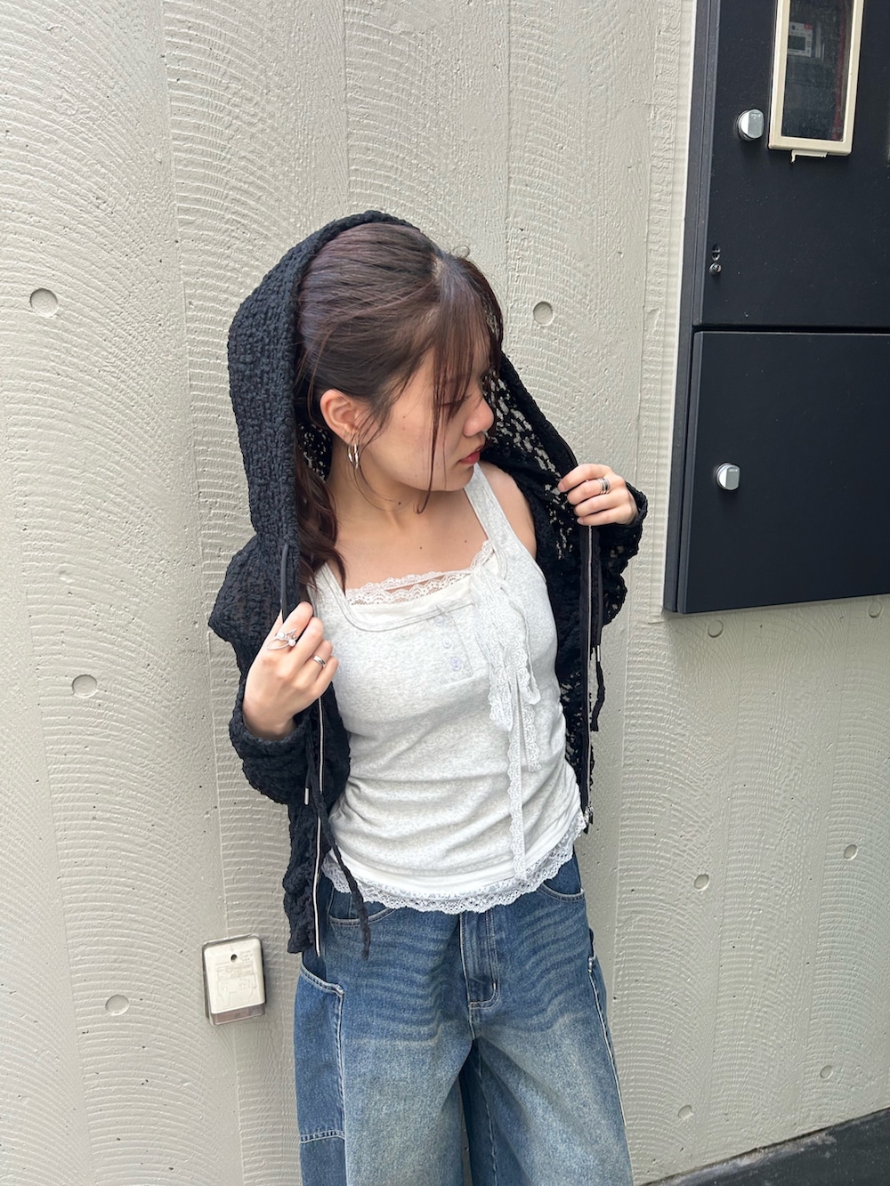 ホワイト系のキャミソール、ブラック系のパーカー、ブルー系のデニムパンツを着用したレディースの春コーディネートの4枚目の写真