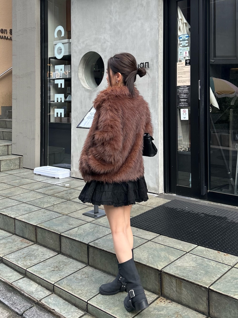 ブラック系のショルダーバッグ、ブラック系のブーツ、ブラック系のスカートを着用したレディースの秋コーディネートの2枚目の写真