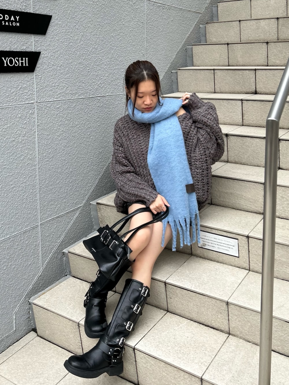 グレー系のニット/セーター、ブラック系のスカート、ブラック系のショルダーバッグを着用したレディースの秋コーディネートの2枚目の写真