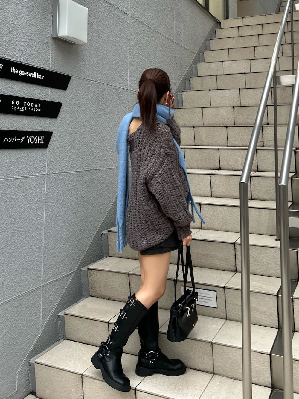 グレー系のニット/セーター、ブラック系のスカート、ブラック系のショルダーバッグを着用したレディースの秋コーディネートの5枚目の写真