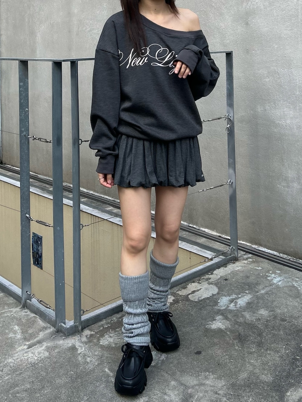 グレー系のスウェット、グレー系のスカート、ブラック系のローファーを着用したレディースの秋コーディネートの2枚目の写真