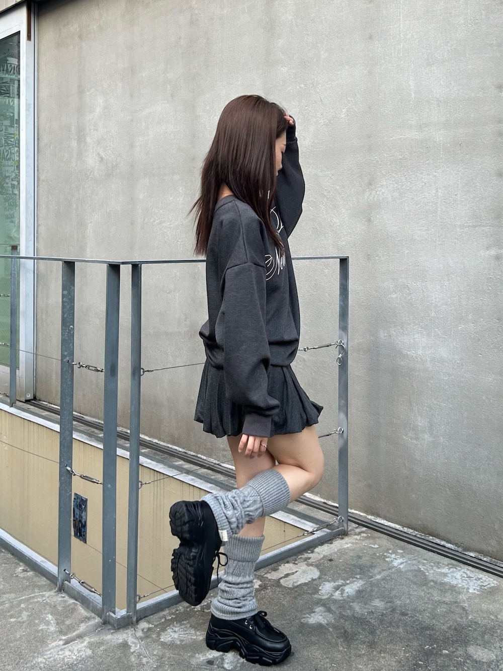 グレー系のスウェット、グレー系のスカート、ブラック系のローファーを着用したレディースの秋コーディネートの3枚目の写真