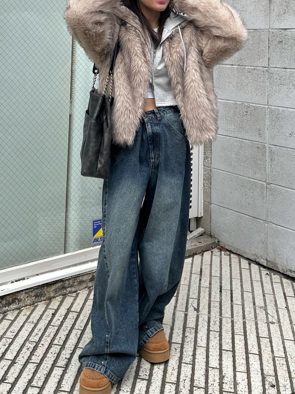 ブルー系のデニムパンツ、ブラック系のトートバッグ、イエロー系のブーツを着用したレディースの秋コーディネートの4枚目の写真