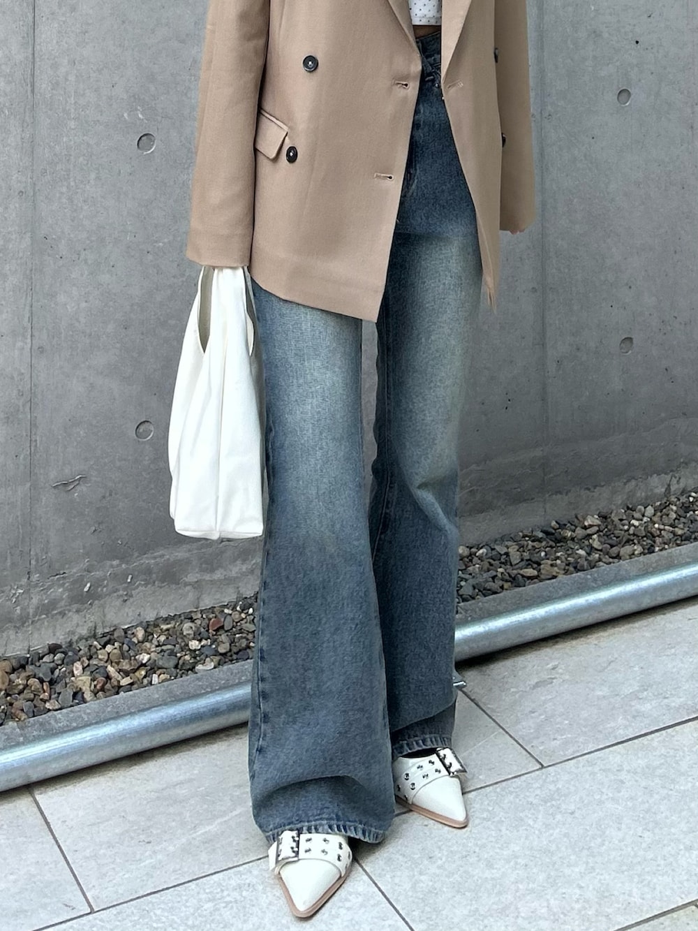 ベージュ系のテーラードジャケット、ホワイト系のカーディガン/ボレロ、ブルー系のデニムパンツを着用したレディースの春コーディネートの4枚目の写真