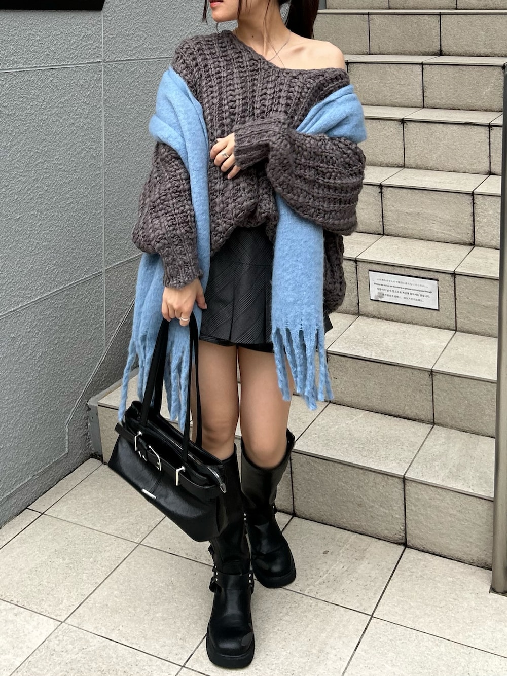 グレー系のニット/セーター、ブラック系のスカート、ブラック系のショルダーバッグを着用したレディースの秋コーディネートの3枚目の写真
