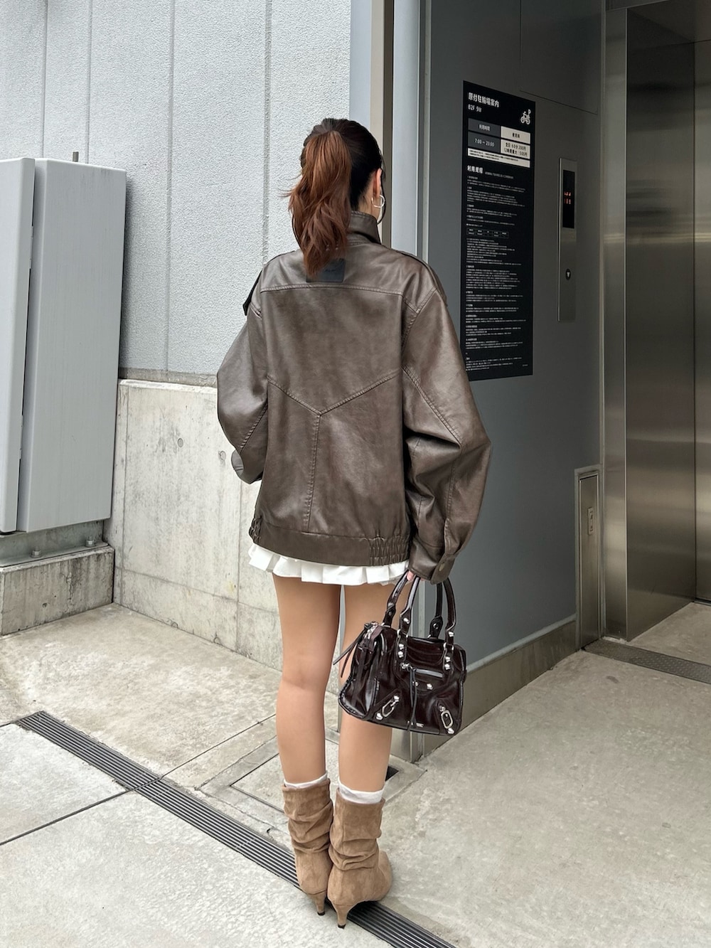 ブラウン系のブルゾン、ホワイト系のTシャツ/カットソー、ホワイト系のスカートを着用したレディースの秋コーディネートの3枚目の写真