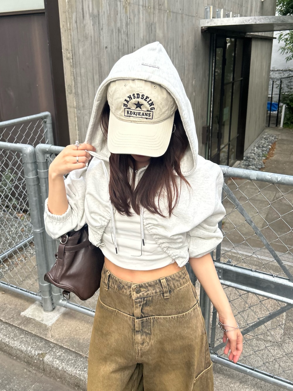 ホワイト系のカーディガン/ボレロ、ベージュ系のデニムパンツ、ホワイト系のキャップを着用したレディースの春コーディネートの6枚目の写真