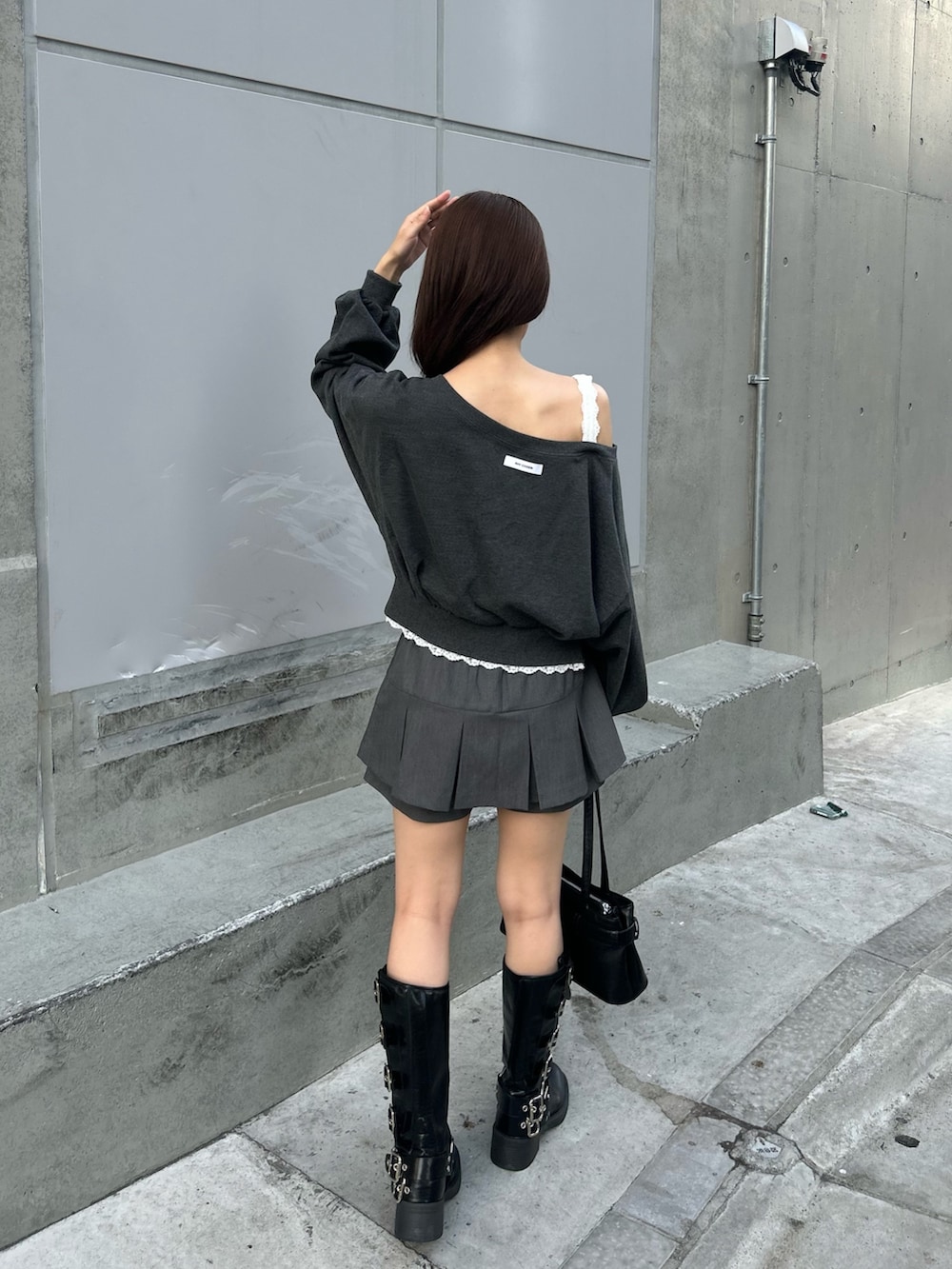 グレー系のスウェット、グレー系のスカート、ブラック系のブーツを着用したレディースの秋コーディネートの3枚目の写真