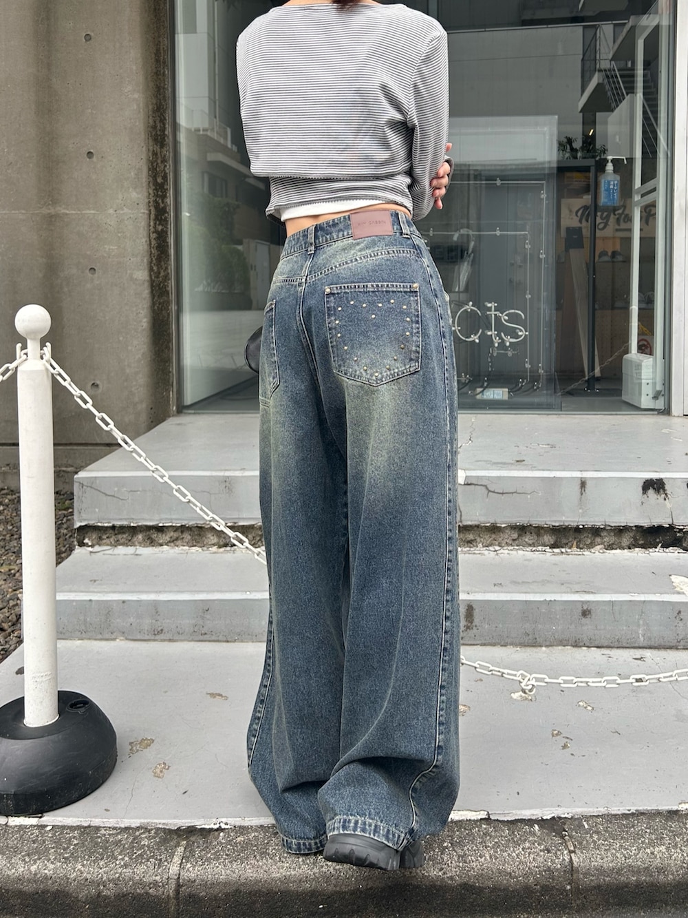 グレー系のTシャツ/カットソー、ブルー系のデニムパンツ、ブラック系のショルダーバッグを着用したレディースの春コーディネートの7枚目の写真