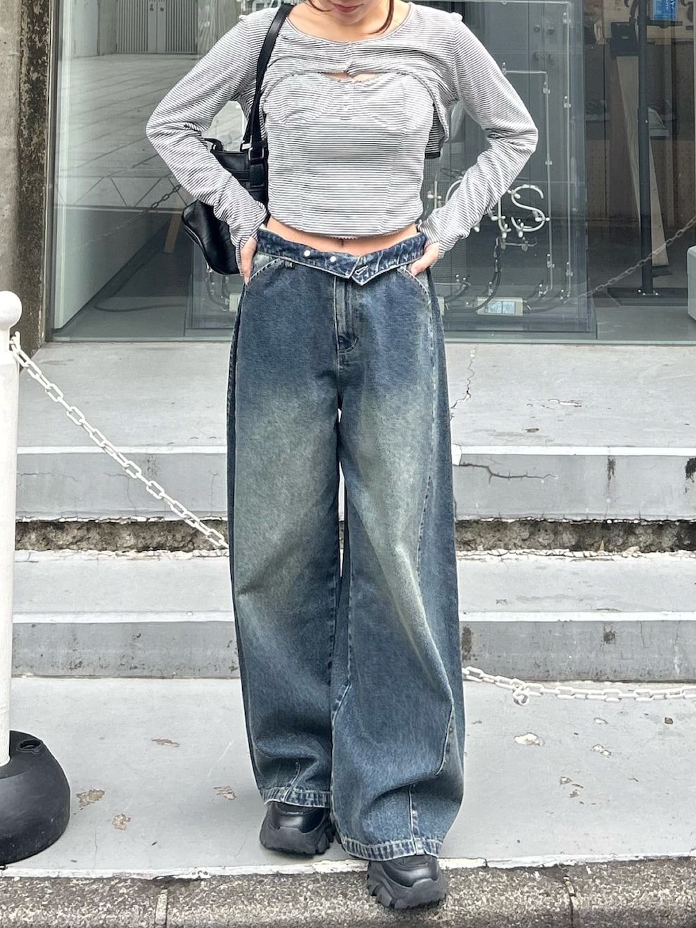 グレー系のTシャツ/カットソー、ブルー系のデニムパンツ、ブラック系のショルダーバッグを着用したレディースの春コーディネートの5枚目の写真