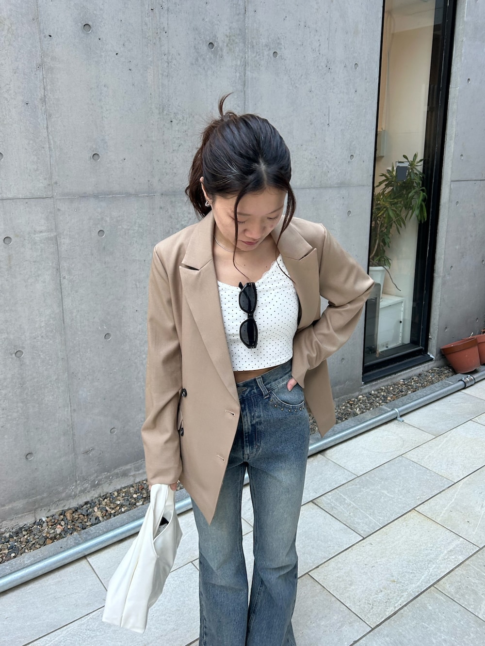 ベージュ系のテーラードジャケット、ホワイト系のカーディガン/ボレロ、ブルー系のデニムパンツを着用したレディースの春コーディネートの5枚目の写真