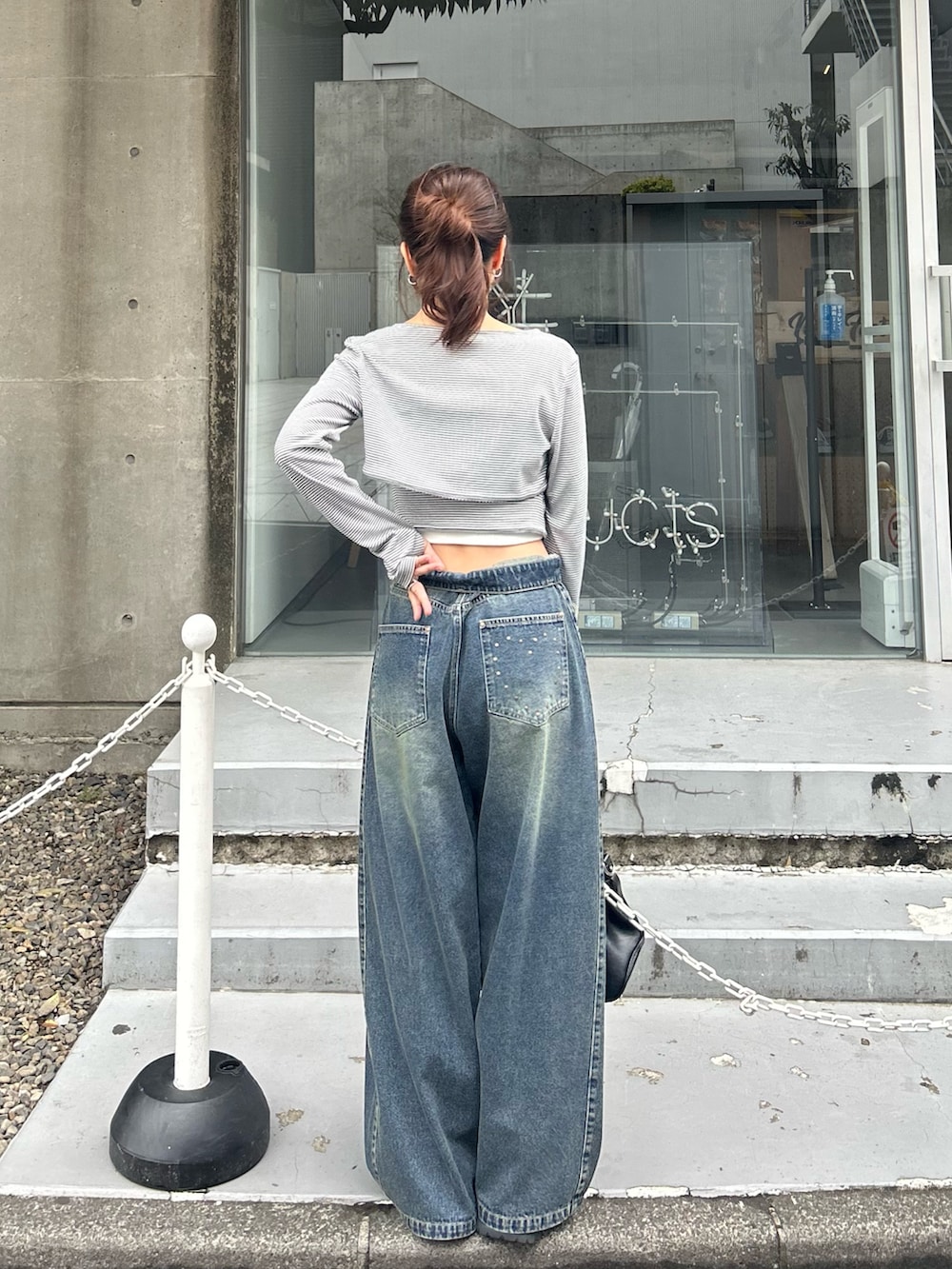 グレー系のTシャツ/カットソー、ブルー系のデニムパンツ、ブラック系のショルダーバッグを着用したレディースの春コーディネートの4枚目の写真