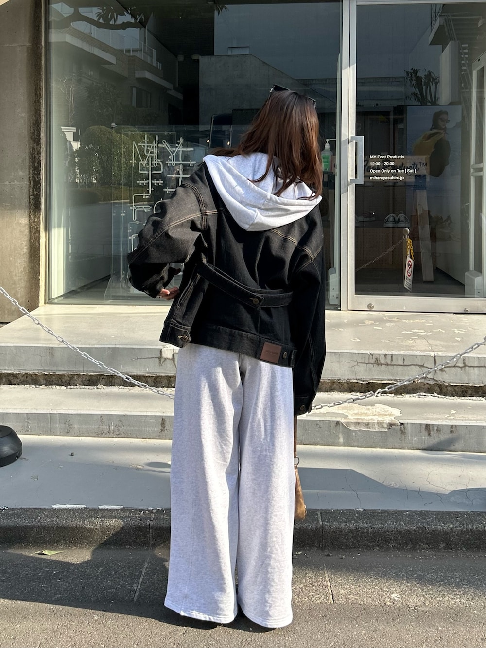 ホワイト系のパーカー、ブラック系のデニムジャケット、グレー系のキャミソールを着用したレディースの春コーディネートの2枚目の写真