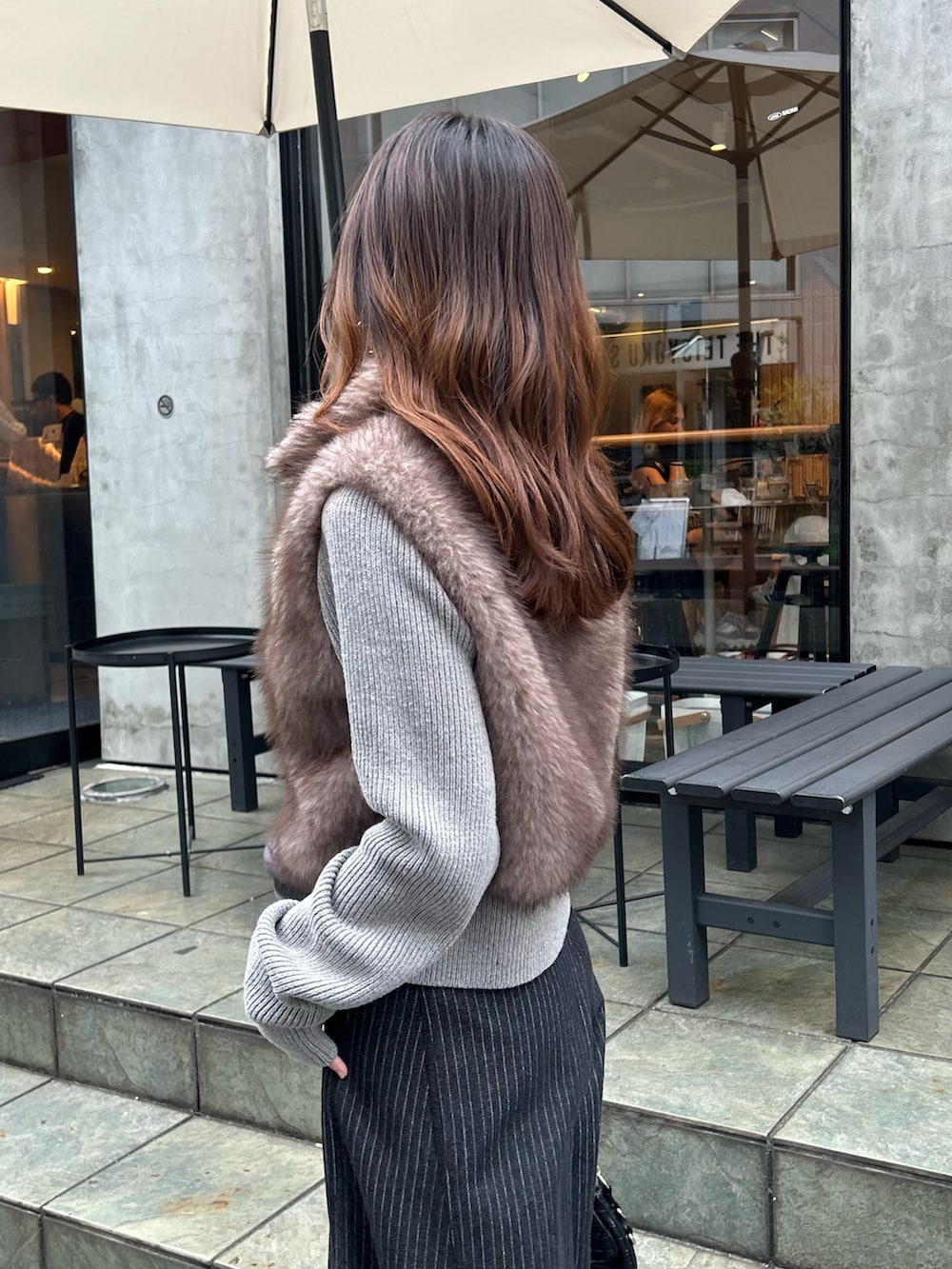 ブラウン系のニット/セーター、ブルー系のデニムパンツ、ブラック系のショルダーバッグを着用したレディースの秋コーディネートの4枚目の写真