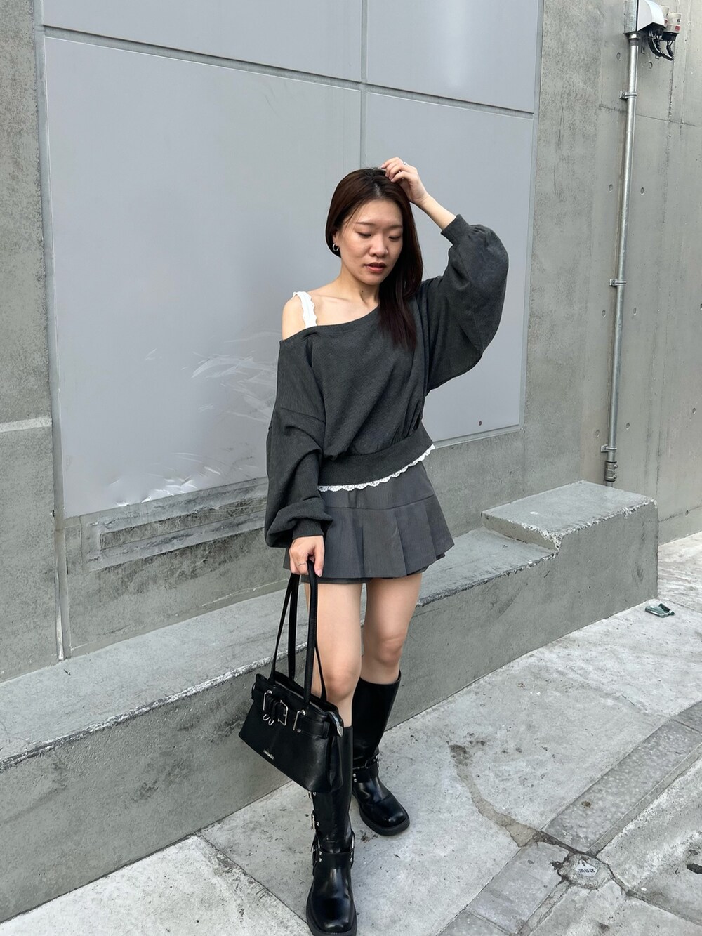 グレー系のスウェット、グレー系のスカート、ブラック系のブーツを着用したレディースの秋コーディネートの2枚目の写真