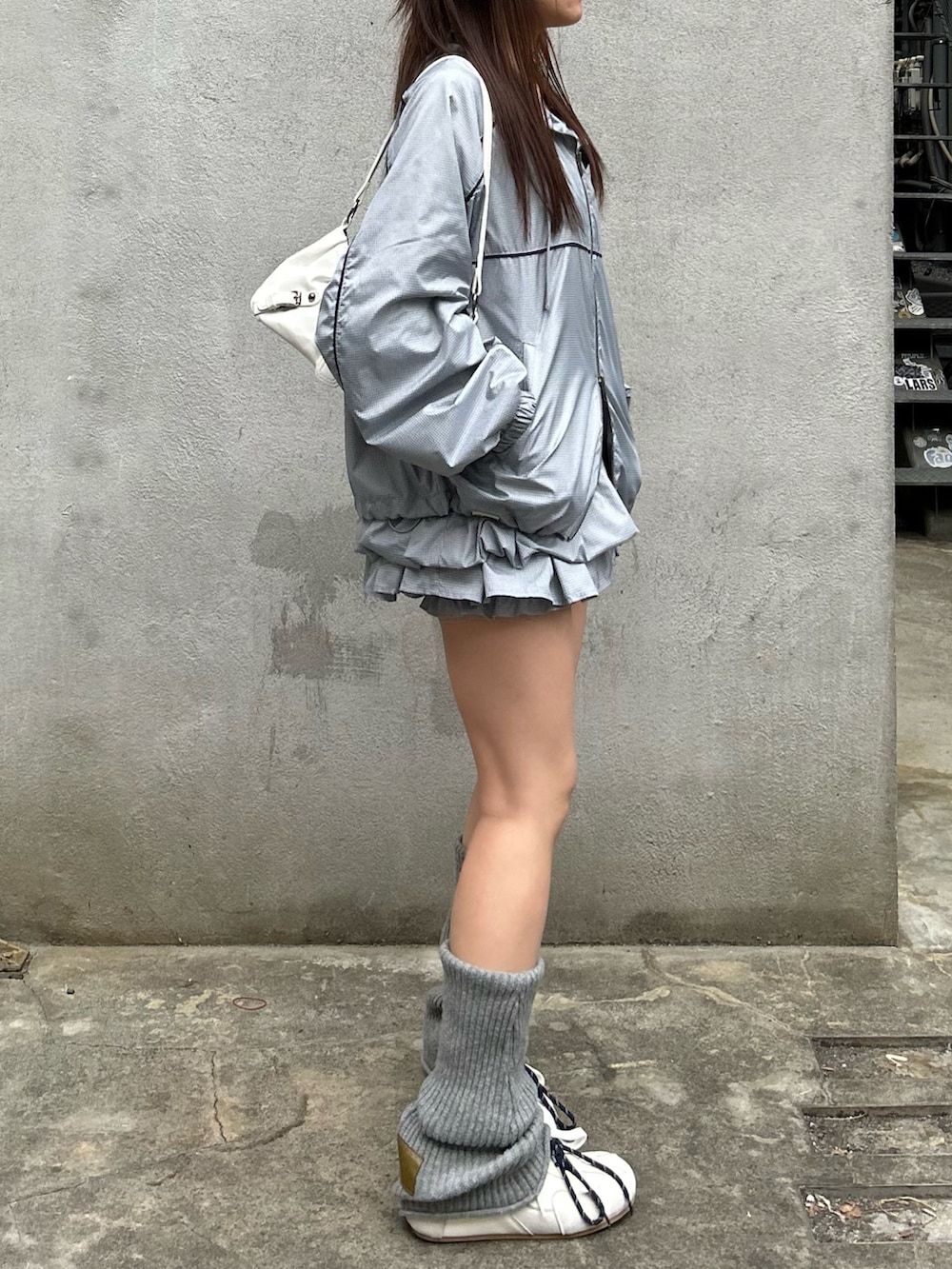 グレー系のブルゾン、グレー系のスカート、ホワイト系のスニーカーを着用したレディースの春コーディネートの2枚目の写真