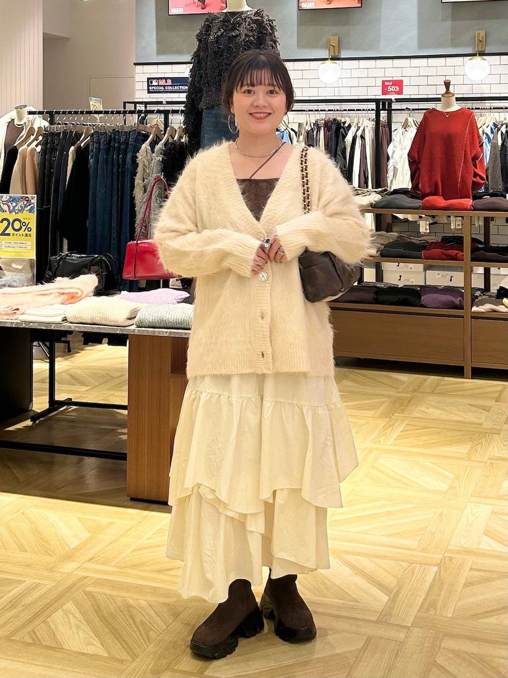 ホワイト系のスカート、ホワイト系のカーディガン/ボレロ、ブラウン系のショルダーバッグを着用したレディースの秋コーディネートの2枚目の写真