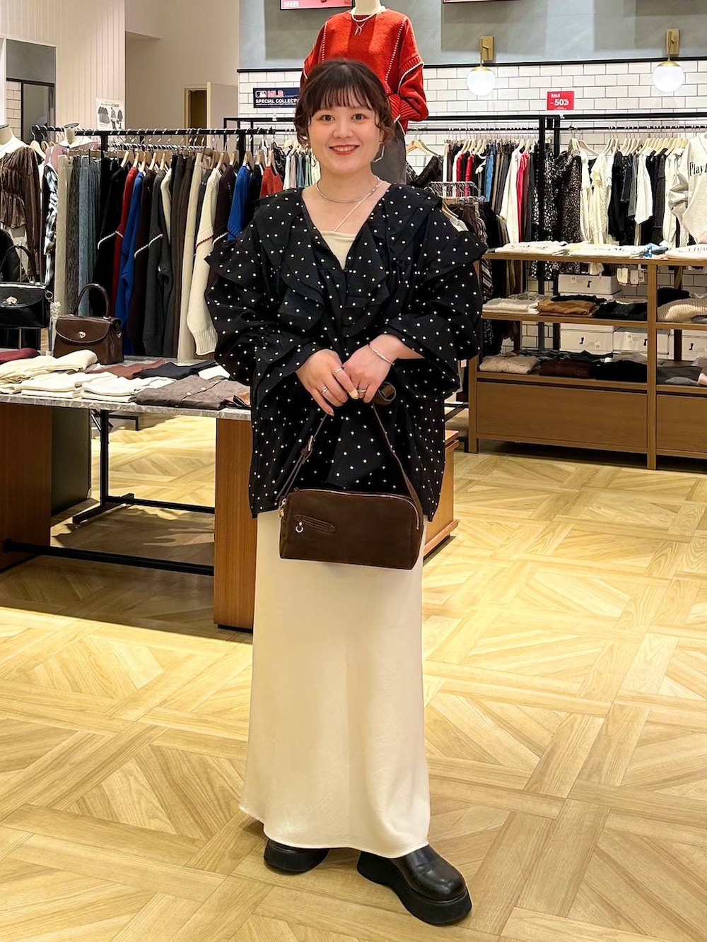 ホワイト系のスカート、ブラウン系のショルダーバッグ、ブラック系のサンダルを着用したレディースの秋コーディネートの2枚目の写真