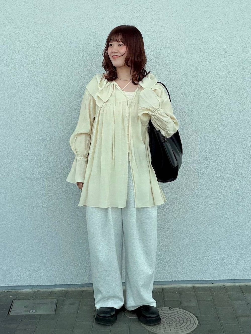 グレー系のスウェットパンツ、ブラック系のサンダル、ホワイト系のキャミソールを着用したレディースの春コーディネートの2枚目の写真