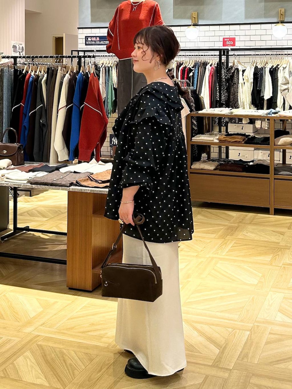 ホワイト系のスカート、ブラウン系のショルダーバッグ、ブラック系のサンダルを着用したレディースの秋コーディネートの4枚目の写真