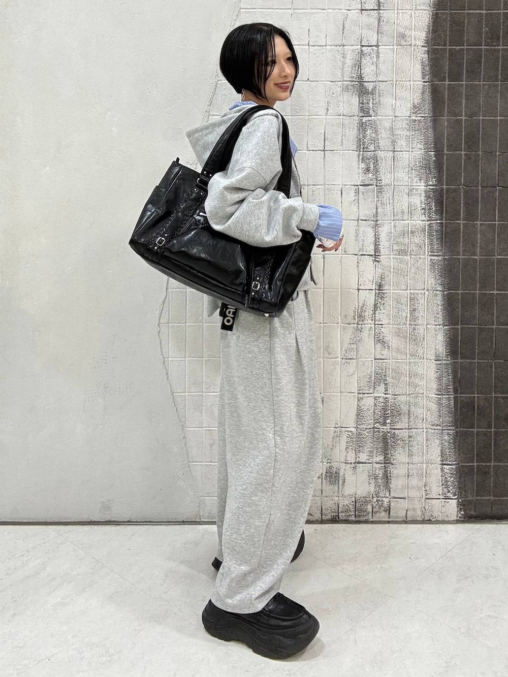 ブラック系のローファー、グレー系のパーカー、ブラック系のトートバッグを着用したレディースの春コーディネートの4枚目の写真