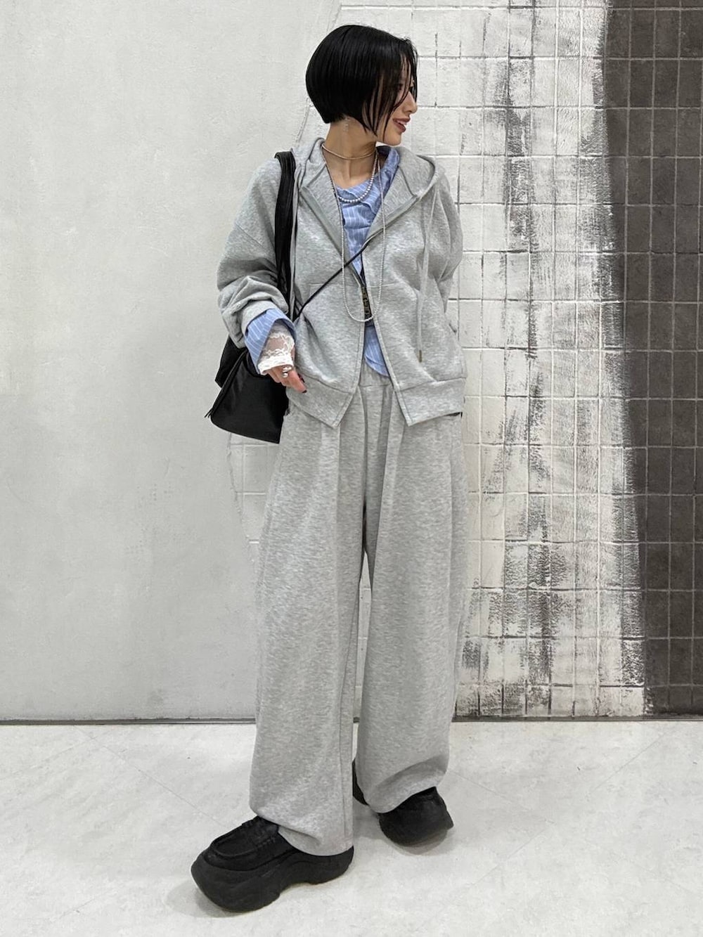 ブラック系のローファー、グレー系のパーカー、ブラック系のトートバッグを着用したレディースの春コーディネートの3枚目の写真