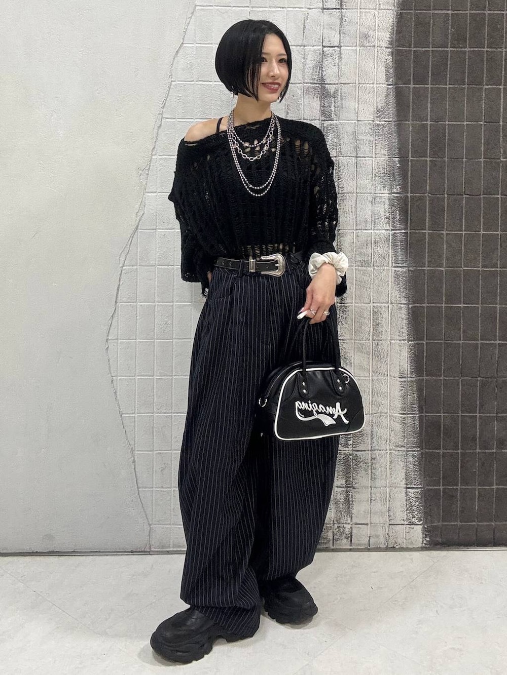 ブラック系のブーツ、ブルー系のスラックス、ブラック系のショルダーバッグを着用したレディースの秋コーディネートの2枚目の写真