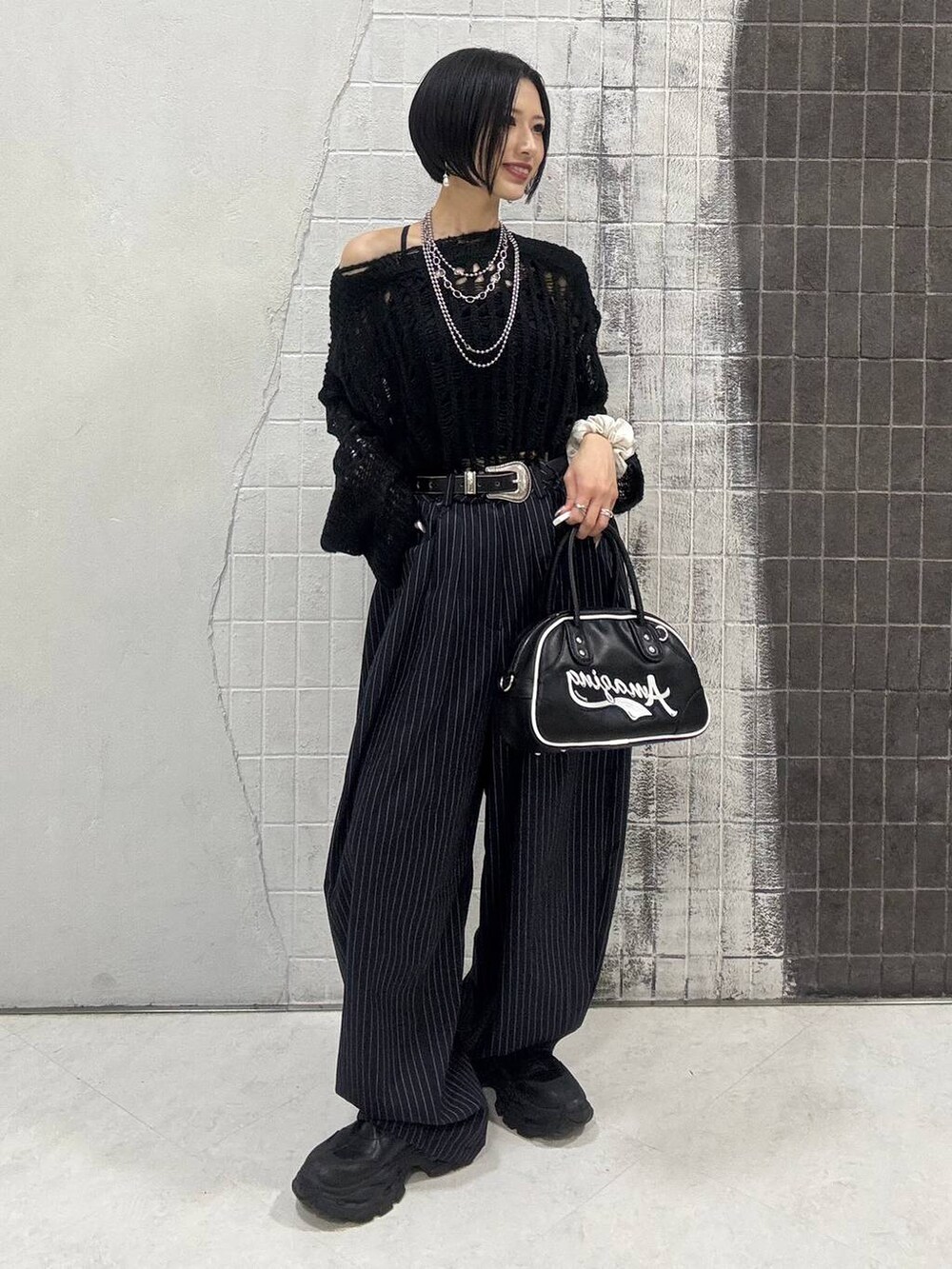 ブラック系のブーツ、ブルー系のスラックス、ブラック系のショルダーバッグを着用したレディースの秋コーディネートの3枚目の写真