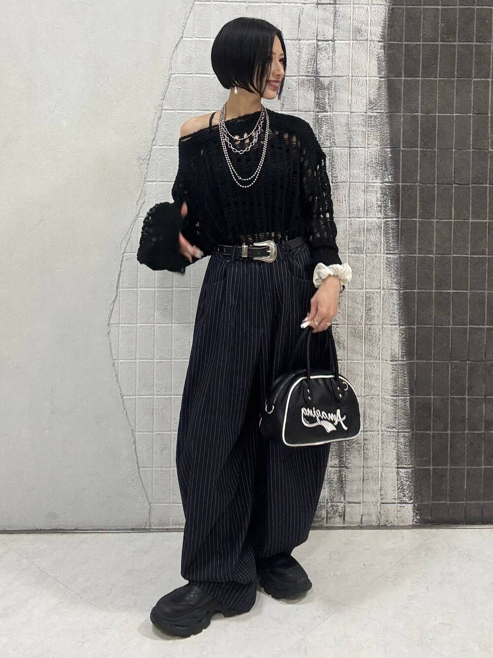 ブラック系のブーツ、ブルー系のスラックス、ブラック系のショルダーバッグを着用したレディースの秋コーディネートの4枚目の写真