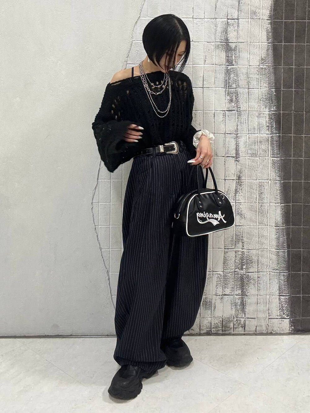 ブラック系のブーツ、ブルー系のスラックス、ブラック系のショルダーバッグを着用したレディースの秋コーディネートの9枚目の写真