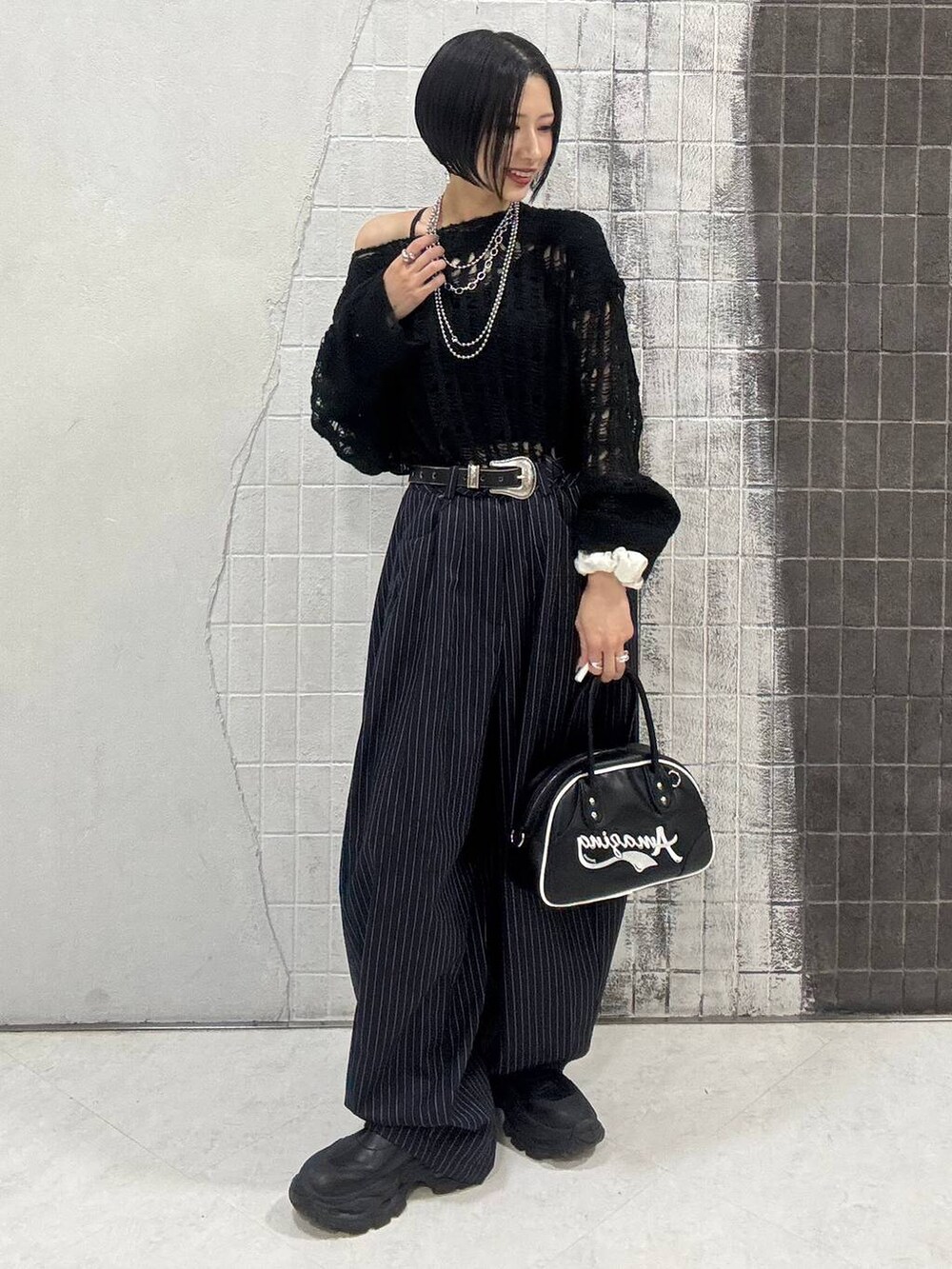 ブラック系のブーツ、ブルー系のスラックス、ブラック系のショルダーバッグを着用したレディースの秋コーディネートの5枚目の写真