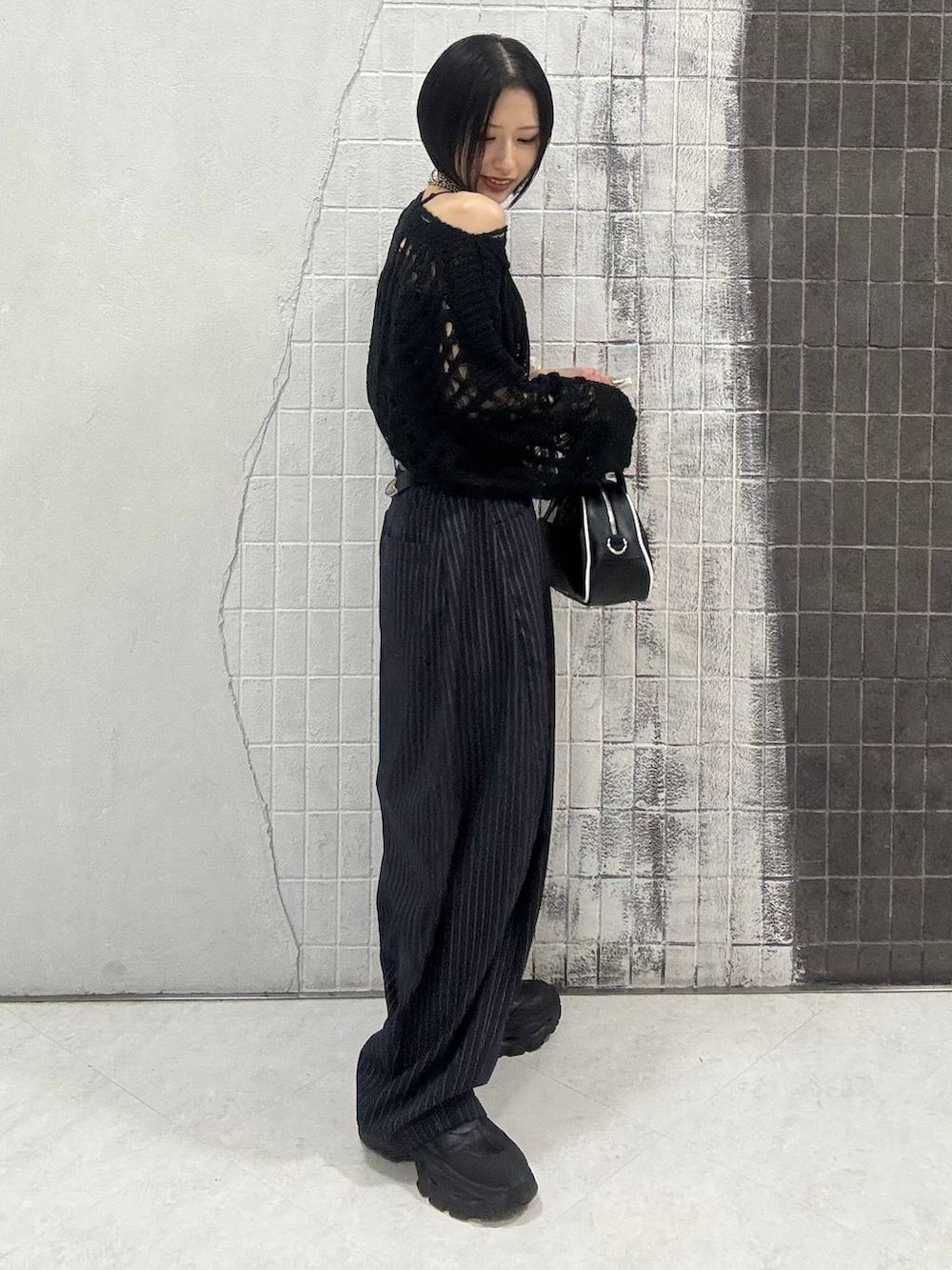 ブラック系のブーツ、ブルー系のスラックス、ブラック系のショルダーバッグを着用したレディースの秋コーディネートの6枚目の写真