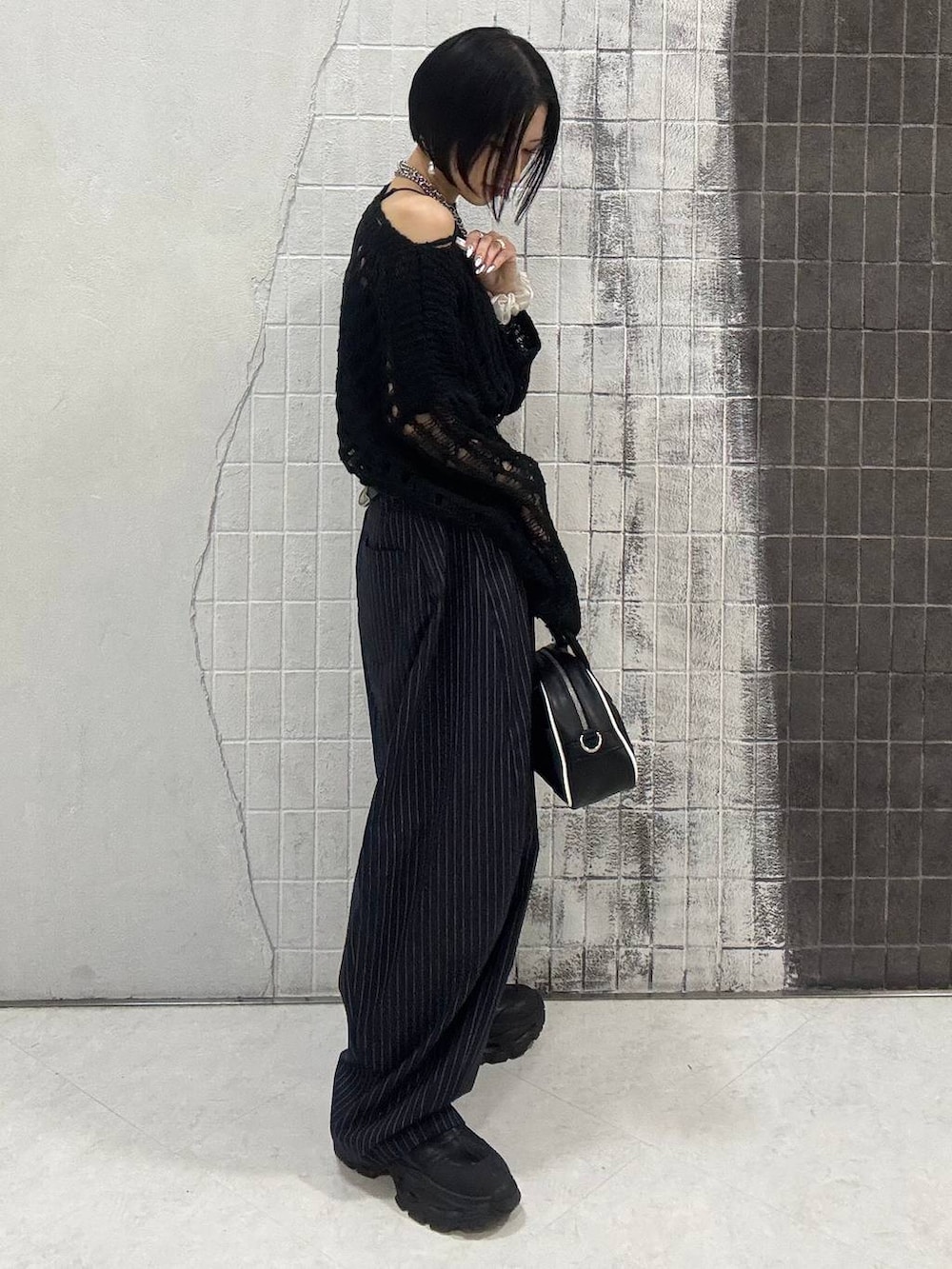 ブラック系のブーツ、ブルー系のスラックス、ブラック系のショルダーバッグを着用したレディースの秋コーディネートの7枚目の写真