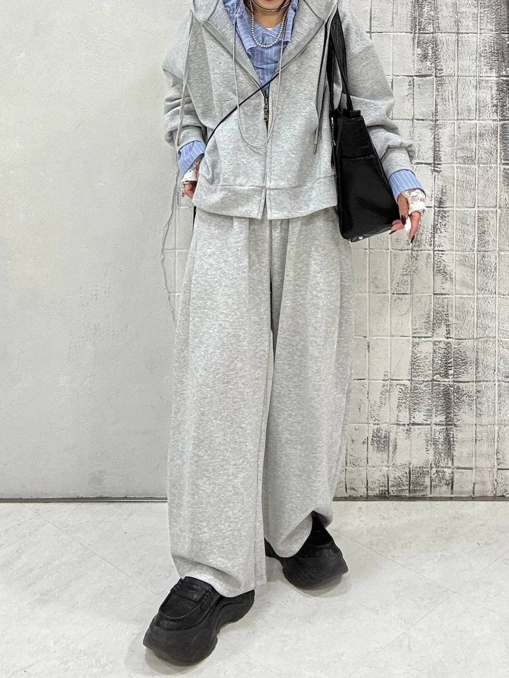 ブラック系のローファー、グレー系のパーカー、ブラック系のトートバッグを着用したレディースの春コーディネートの5枚目の写真