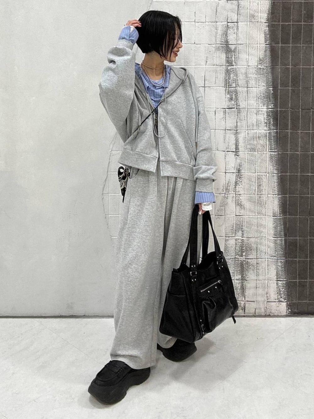 ブラック系のローファー、グレー系のパーカー、ブラック系のトートバッグを着用したレディースの春コーディネートの2枚目の写真